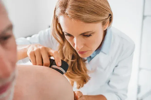 Dermatologist examining a mole on a patient's shoulder