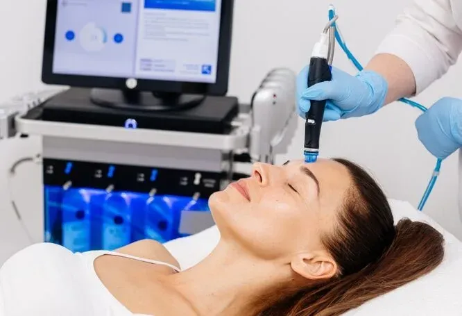 Woman receiving a facial treatment beside a treatment machine