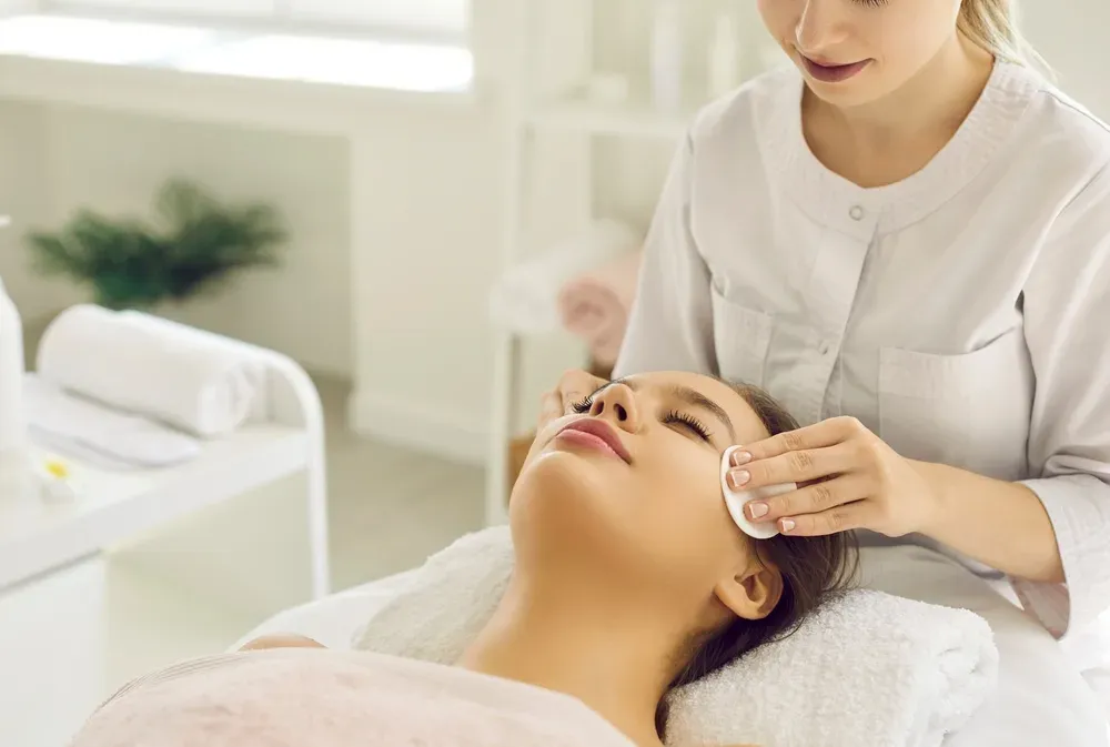 Aesthetician cleansing a woman's face