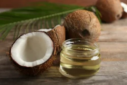 coconut oil and coconuts on wooden surface - - Does Coconut Oil Help With Eczema? - Palm Beach Dermatology Group