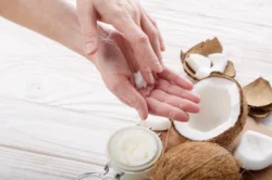 coconut oil on wooden with hands - Does Coconut Oil Help With Eczema? - Palm Beach Dermatology Group